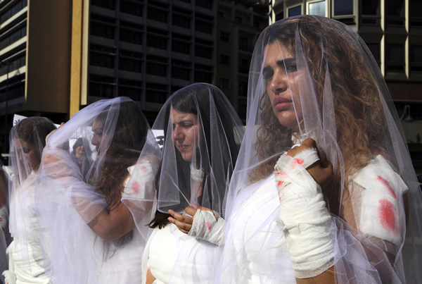 Lebanese women dressed in bloody bridal gowns protest law that allows rapists to avoid prosecution if they marry their victims. AP Photo/Bilal Hussein
